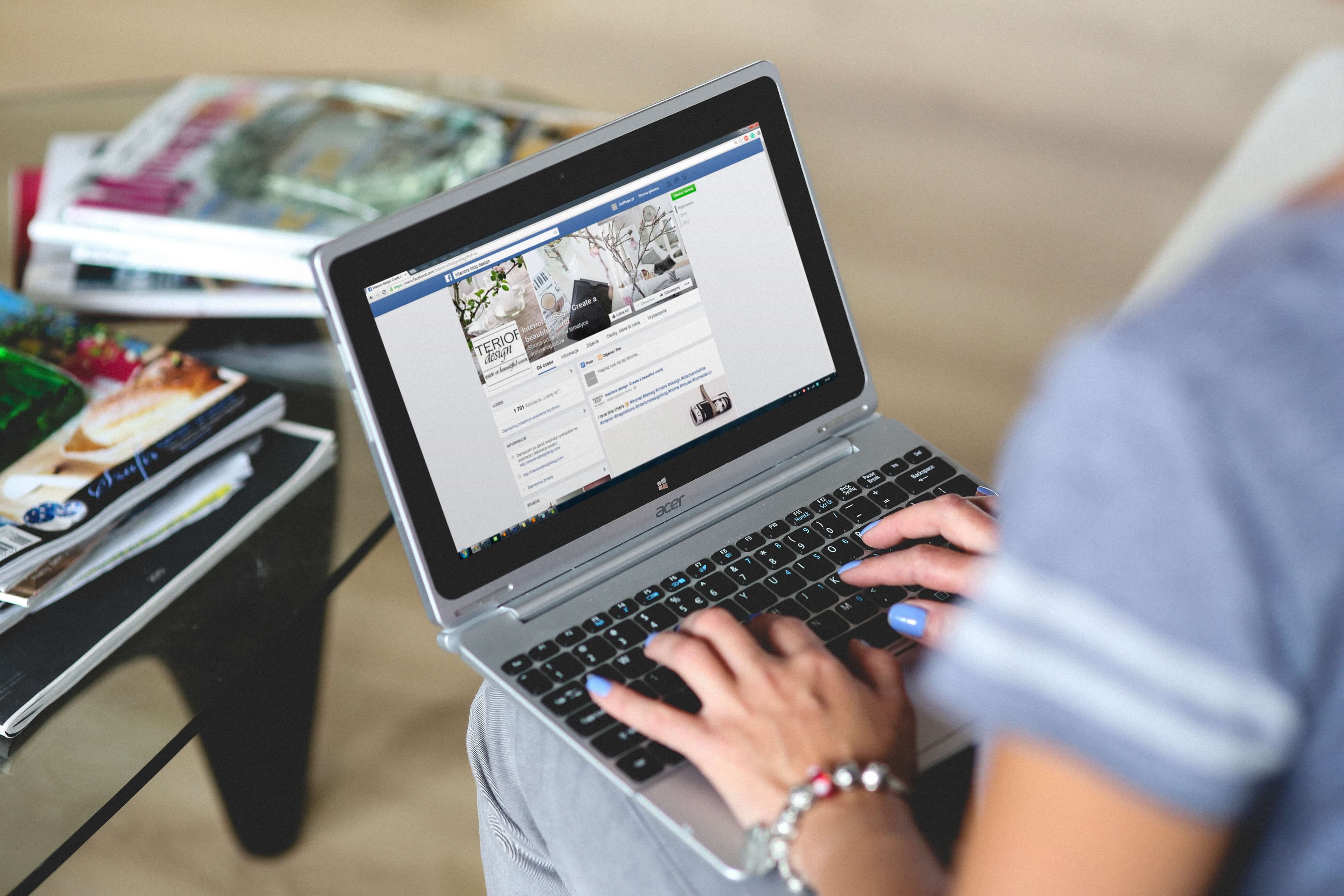 a person typing on a laptop with facebook open